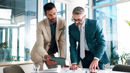 Business, men and meeting on tablet at office of planning, financial documents and company growth. People, collaboration and paperwork with profit graph, investment report and teamwork of opportunity