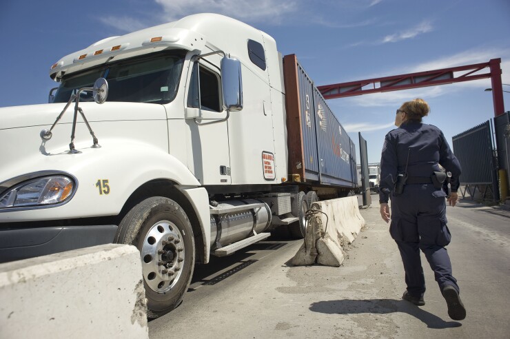 A U.S. Customs and Border Protection officer walks next to a truck entering from Mexico at the Otay Mesa Cargo Port of Entry in San Diego, California, U.S., on May 23, 2017