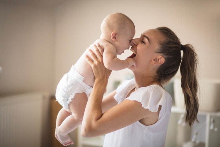Mom holding baby in the air, smiling