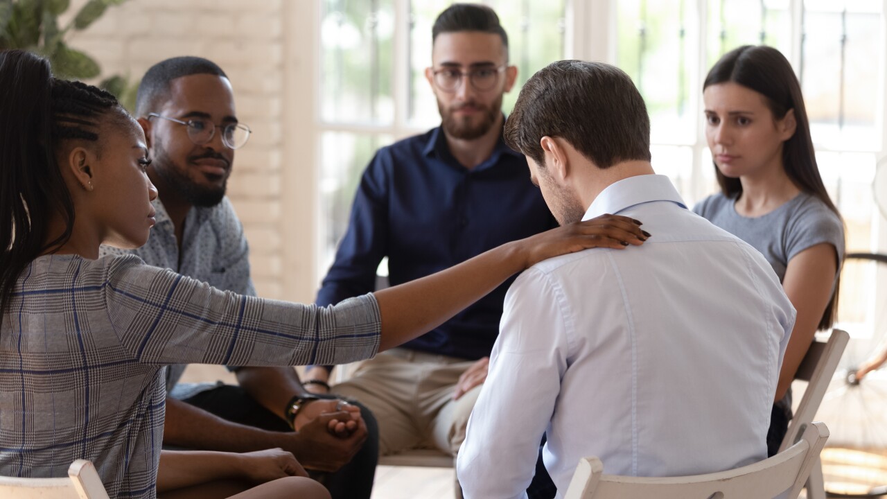 A support group of five comforts a fellow member.