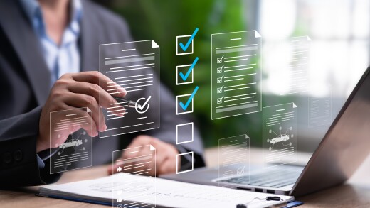 A person using a laptop with a clipboard next to it and a holographic image of a checklist overlayed.