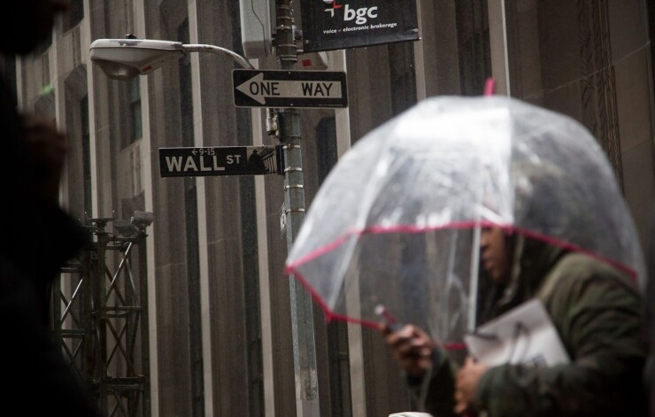 A pedestrian carries an umbrella while walking along Wall Street near the New York Stock Exchange.