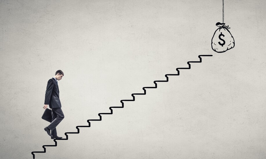 A somber businessman walking up a staircase to a bag of money