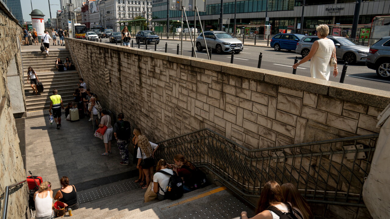 People wait in the shade during hot temperatures outside the Central Railway Station in Warsaw, Poland, on Aug. 5.