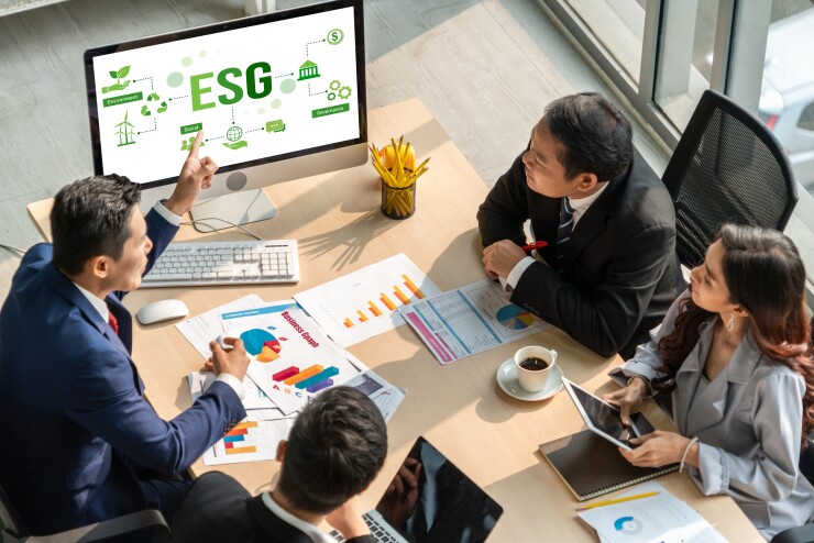 People sitting around a table with ESG on a monitor.