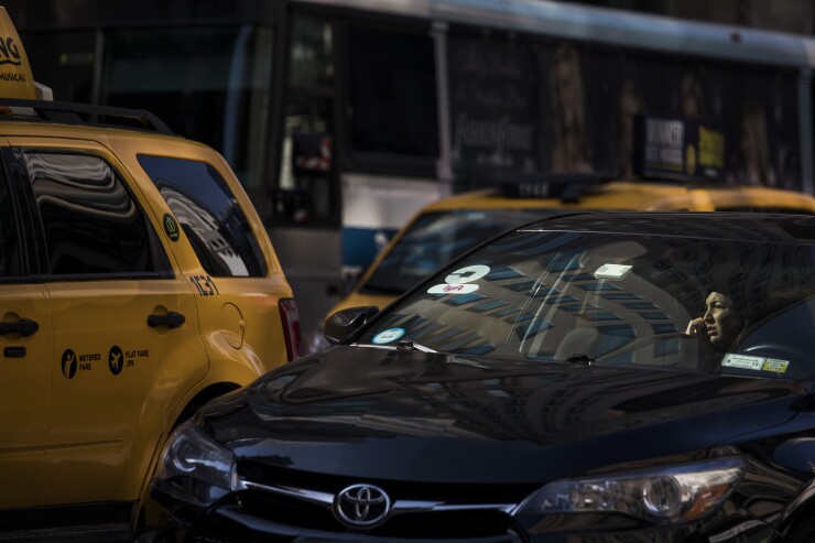 Taxis and Lyft cars are next to each other on NYC street.