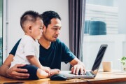 AAPI family - Asian father working on laptop computer with child