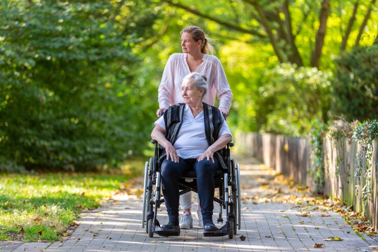 Younger woman pushing an older woman in a wheelchair