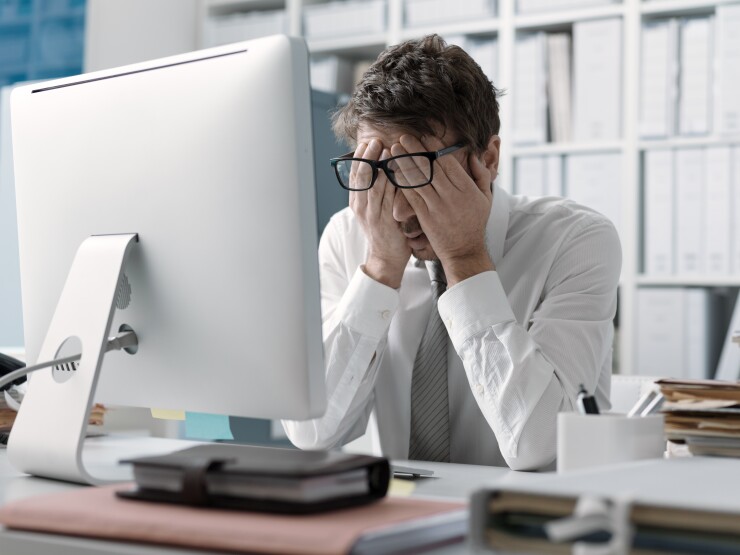 Employee in front of computer with head in his hands