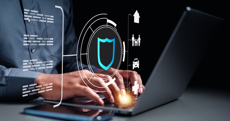 Person typing on a laptop with various figures representing insurance floating above the keyboard.