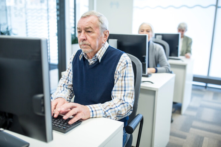 Active seniors attending computer course, working on PC