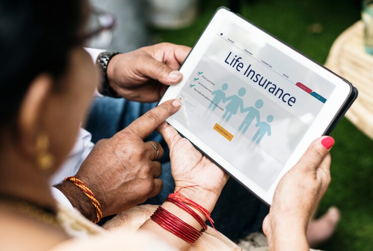 Two people looking at a tablet with a life insurance graphic on the screen.