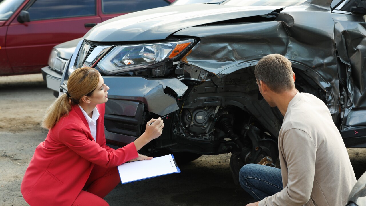 Adjuster and client noting damage to car for claim