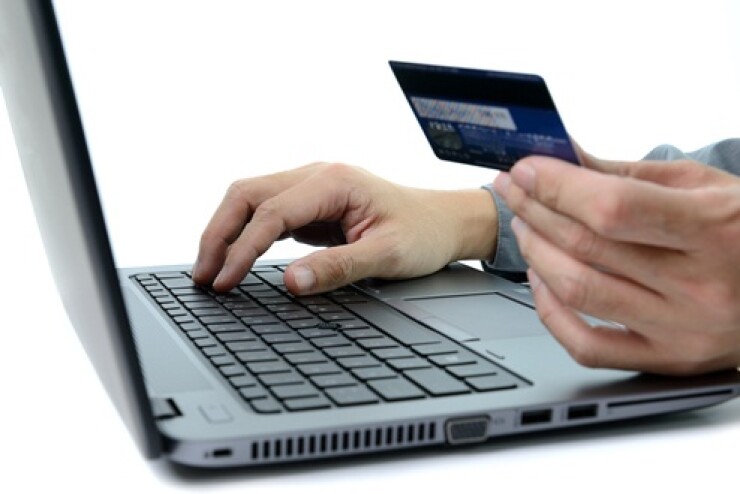 Person holding a credit card and shopping on a computer.