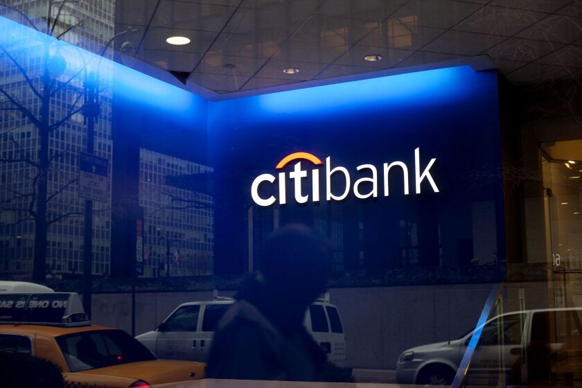 A pedestrian is reflected in a Citigroup bank branch.