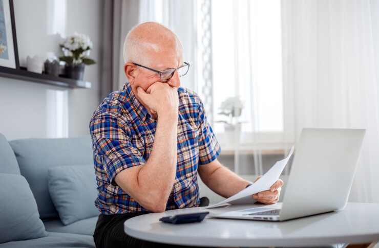 Man looking at paperwork and his computer