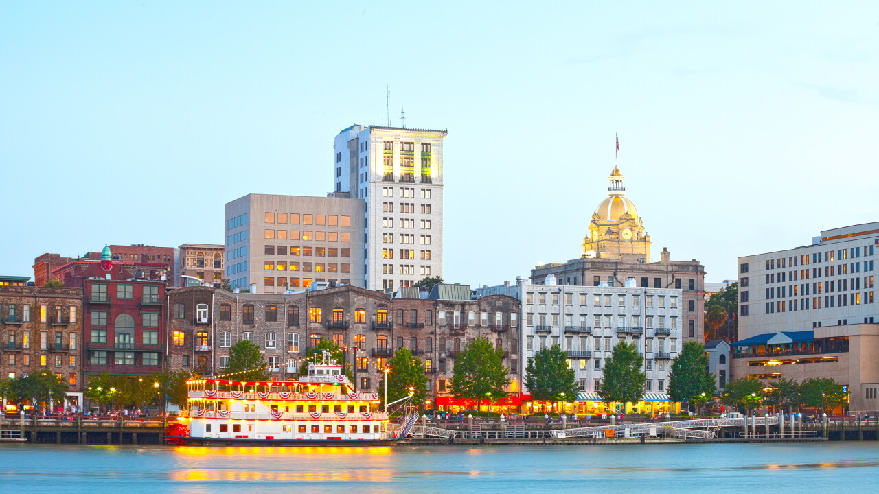 Savannah, Georgia, skyline of historic downtown at sunset with illuminated buildings and steam boats