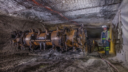 Coal miner next to large mining machine underground