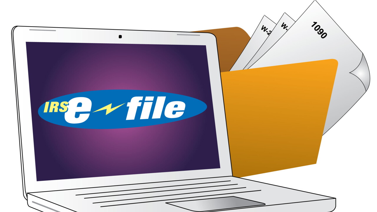 IRS e-file on laptop screen in front of tax forms in folder