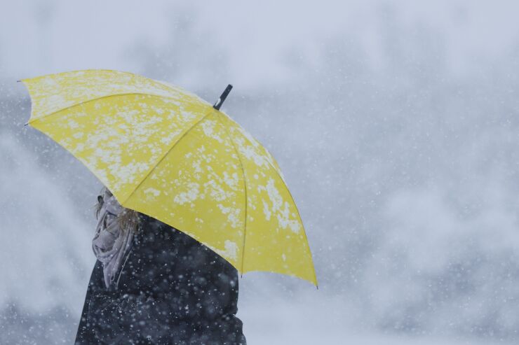 A pedestrian with an umbrella struggles through a snowstorm