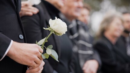 A person holds a flower at a funeral service.