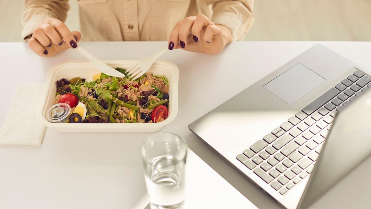 Woman eating a salad while at her desk