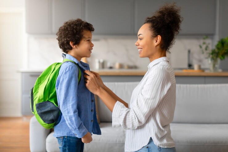 Mom helping son put on backpack