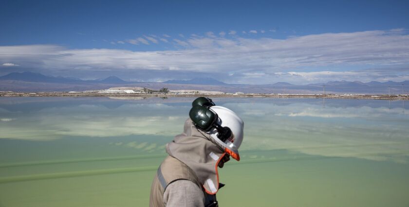 A visitor walks past a brine lake at a lithium mine on the Atacama salt flat in the Atacama Desert, Chile.