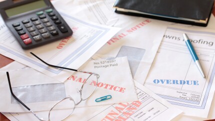 "Overdue Unpaid Bills on Table with Calculator and Cheque Book