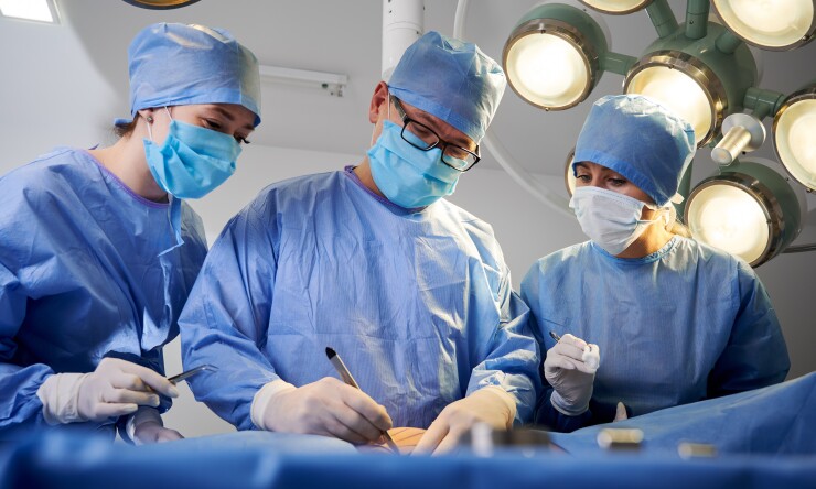 Surgeons performing surgery, two surgeons observing