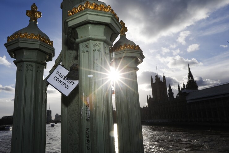 A sign reading 'Passport Control' hangs from padlocks attached to Westminster Bridge as the Houses of Parliament stands on the bank of the River Thames in London.