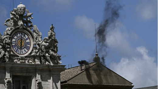 A picture of black smoke billowing from a pipe on the roof of the Vatican.