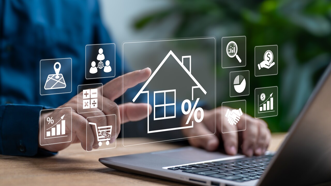 A person using a laptop with a holographic image of a house and a percentage sign.