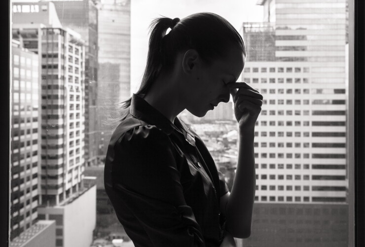 Woman in office, stressed, fingers pressed on bridge of nose