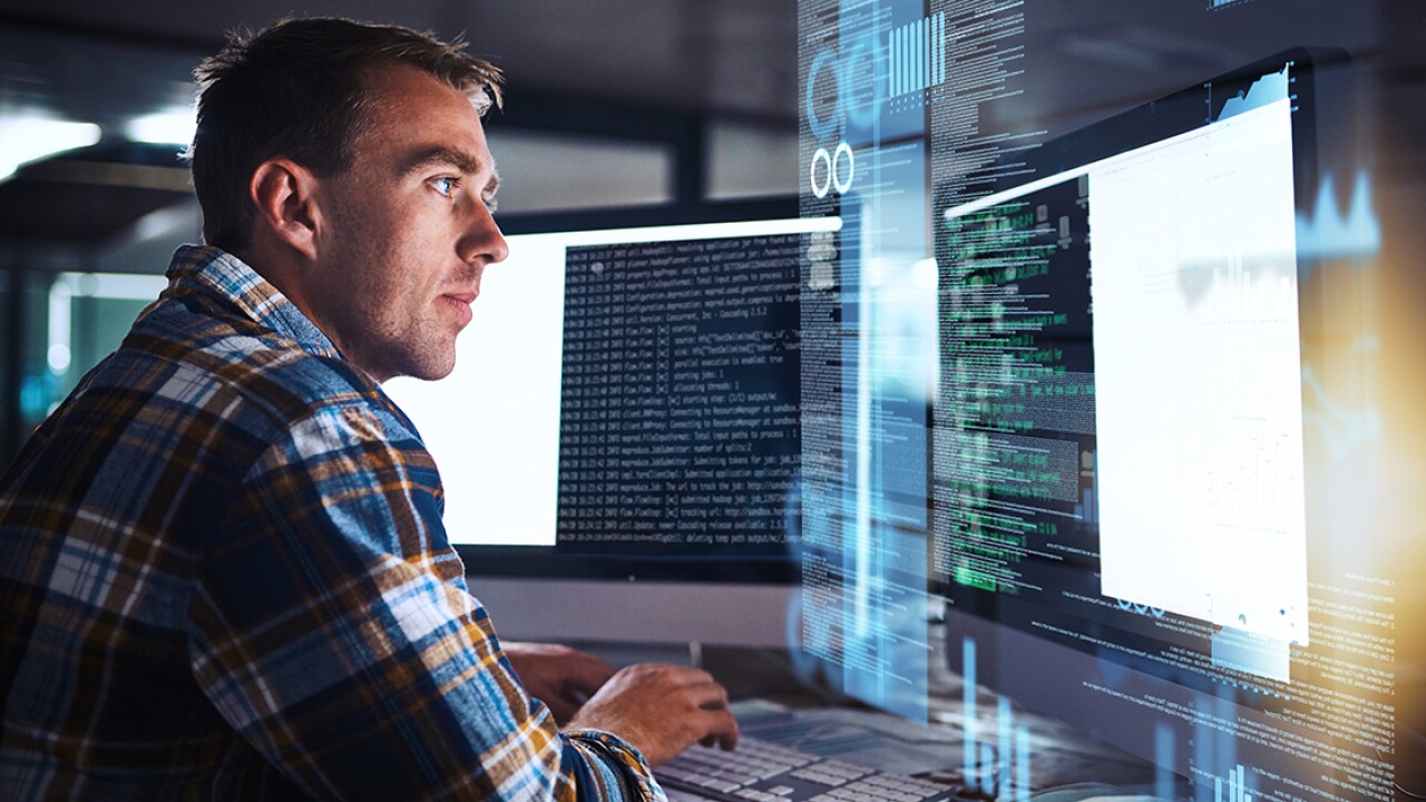 Man sitting in front of a compute screen with data on it.