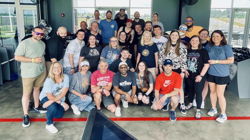Smiley Technologies team members wear assorted Star Wars t-shorts at Top Golf driving range.