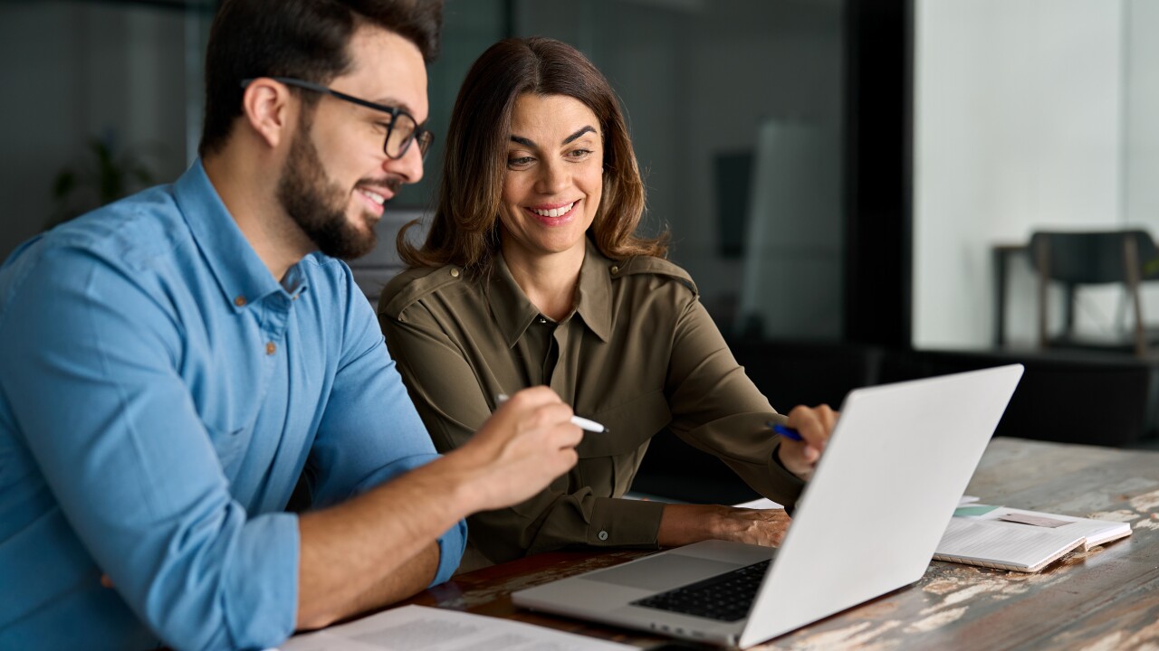 Two employees, man and woman, working, looking at computer