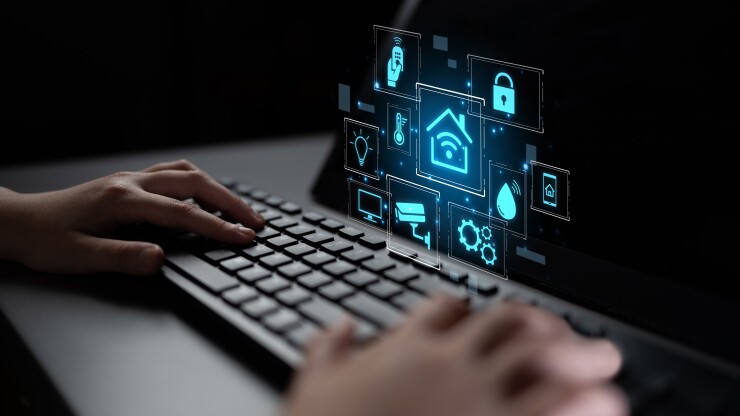 A person using a computer keyboard with a holographic icons that are smart home and the Internet of Things related.