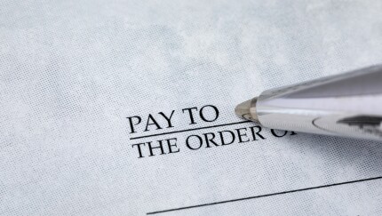 Writing check with pen. Banking, paying bills, and financial fraud concept