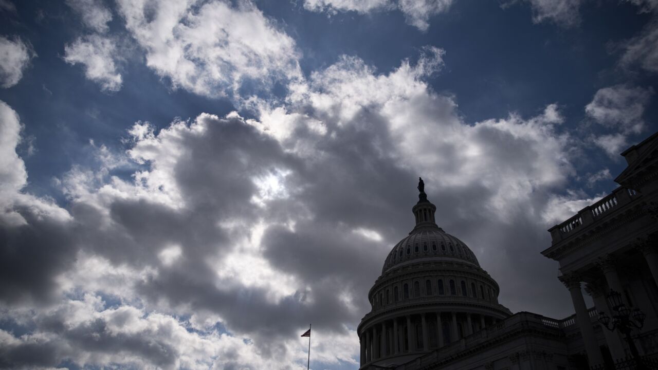 The silhouette of the U.S. Capitol against a cloudy sky