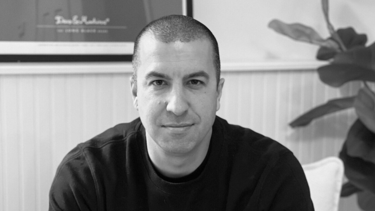 black and white close-up photo of Dakota CEO Ryan Bozarth wearing a black crewneck with a plant behind his left shoulder