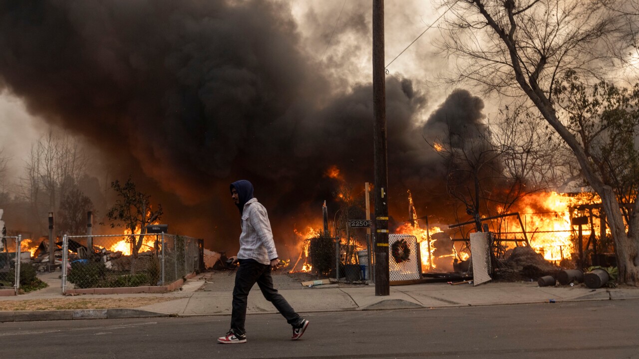 Man walking past burning homes