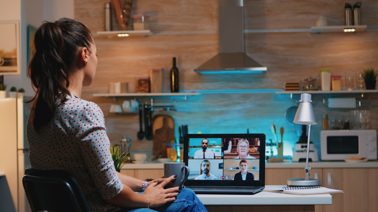 Woman in home office meeting virtually with people on computer