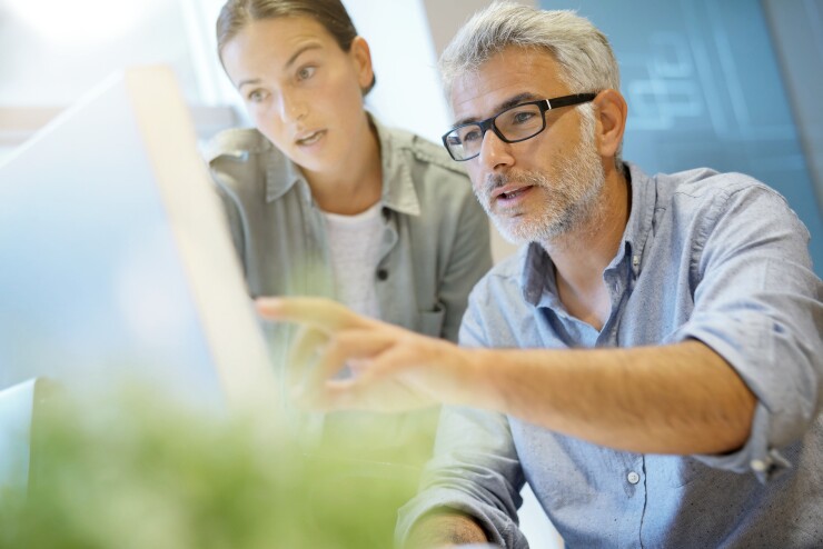 Employees working together with man pointing at computer