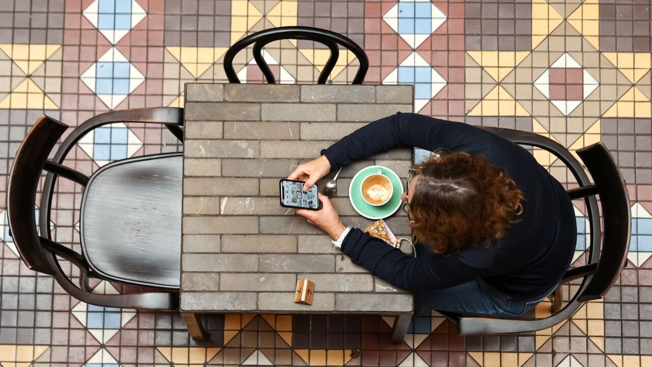 A diner uses a phone at a cafe in Strand Arcade in Sydney, Australia, on Monday, Oct. 11, 2021. Residents of New South Wales who have received both doses of the covid vaccine were on Monday again allowed to start visiting non-essential retail stores, pubs and gyms, with capacity limits. The government eased lockdown measures once 70% of people over age 16 were fully vaccinated. Photographer: Brendon Thorne/Bloomberg