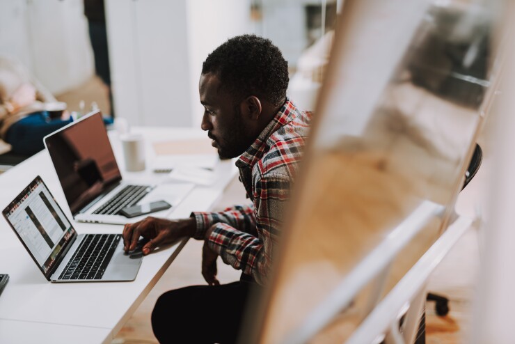 Young employee scrolls on his laptop in the office.