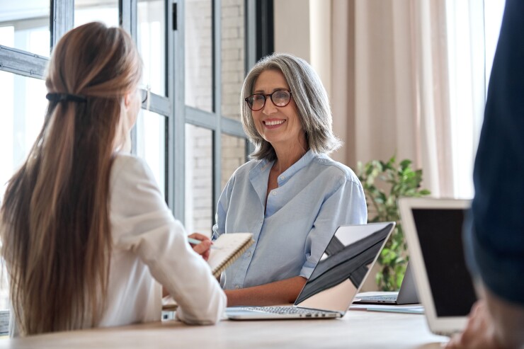 Older woman with short gray hair talking to a younger employee at work
