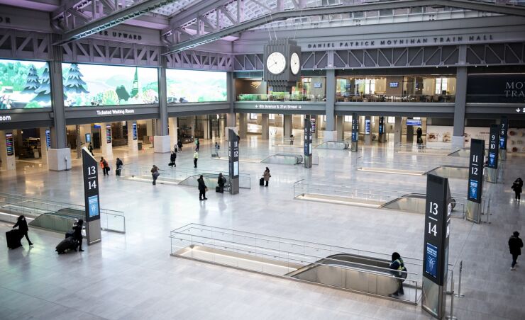 Passengers wearing protective masks walk through Moynihan Train Hall at Pennsylvania Station in New York, U.S., on Friday, Jan. 8, 2020.