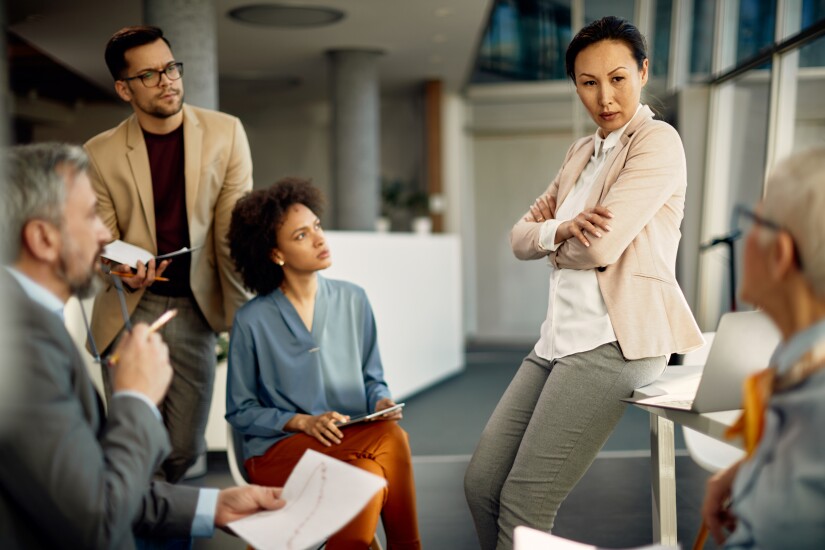 Team sitting in office, leader standing, listening