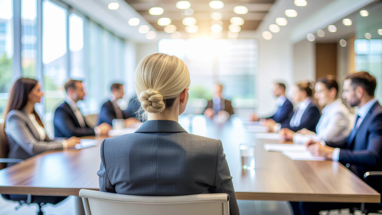 Female leader sitting at head of table, back to camera